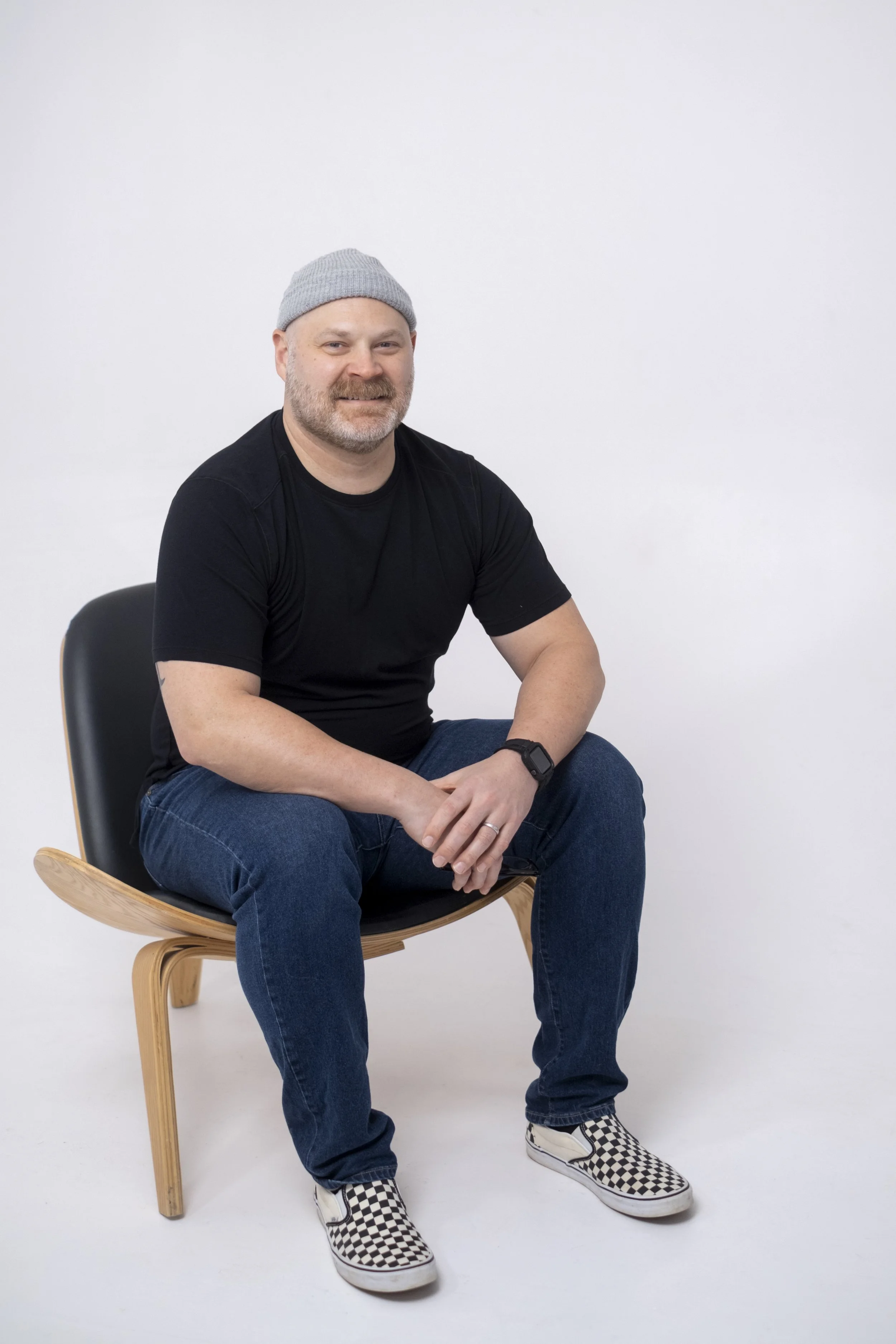 A man poses for a portrait at a photo studio while sitting in a chair in Ann Arbor, Michigan.