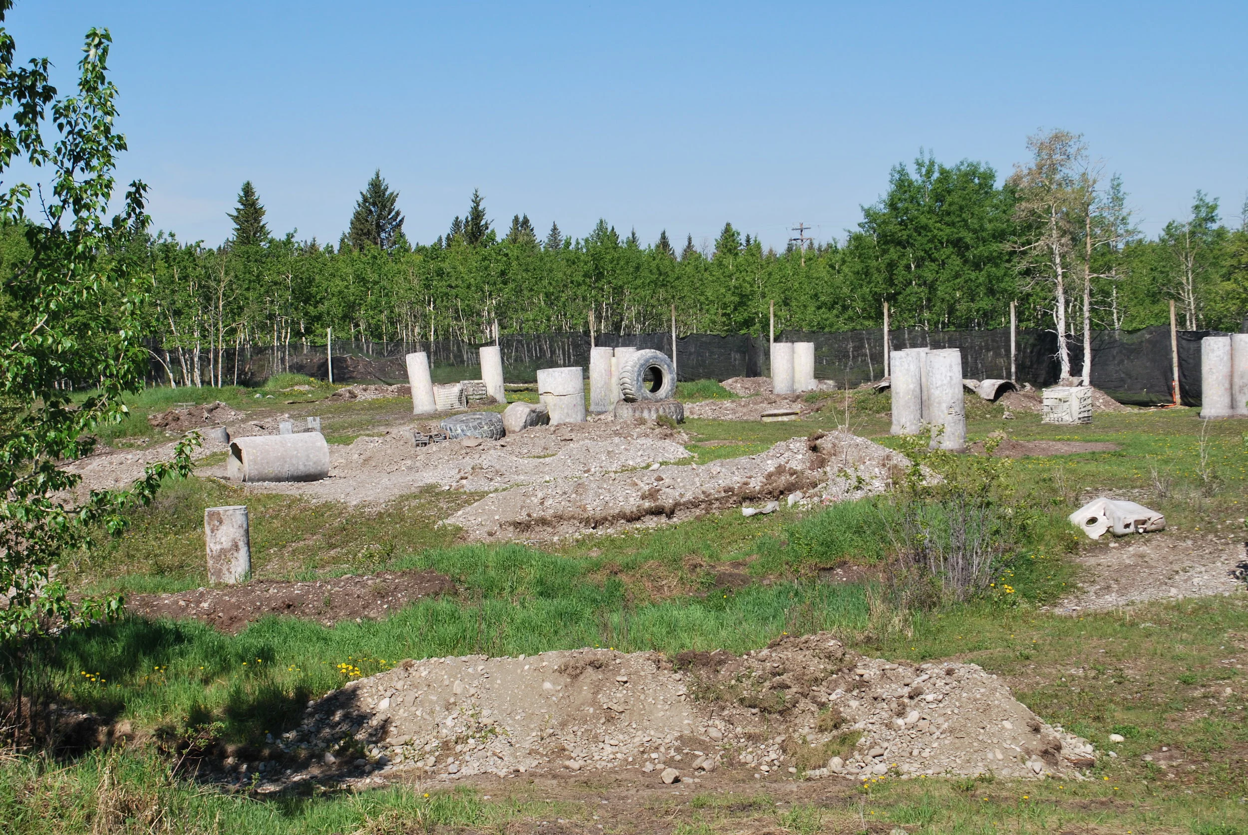 Outdoor paintball field with obstacles and trees