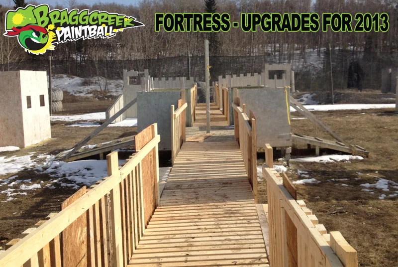 Outdoor paintball field with wooden structures, labeled "Bragg Creek Paintball" and "Fortress - Upgrades for 2013."