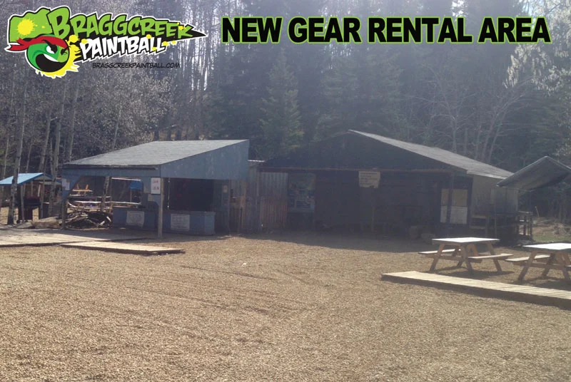 Bragg Creek Paintball new gear rental area with buildings and picnic tables in a wooded setting.
