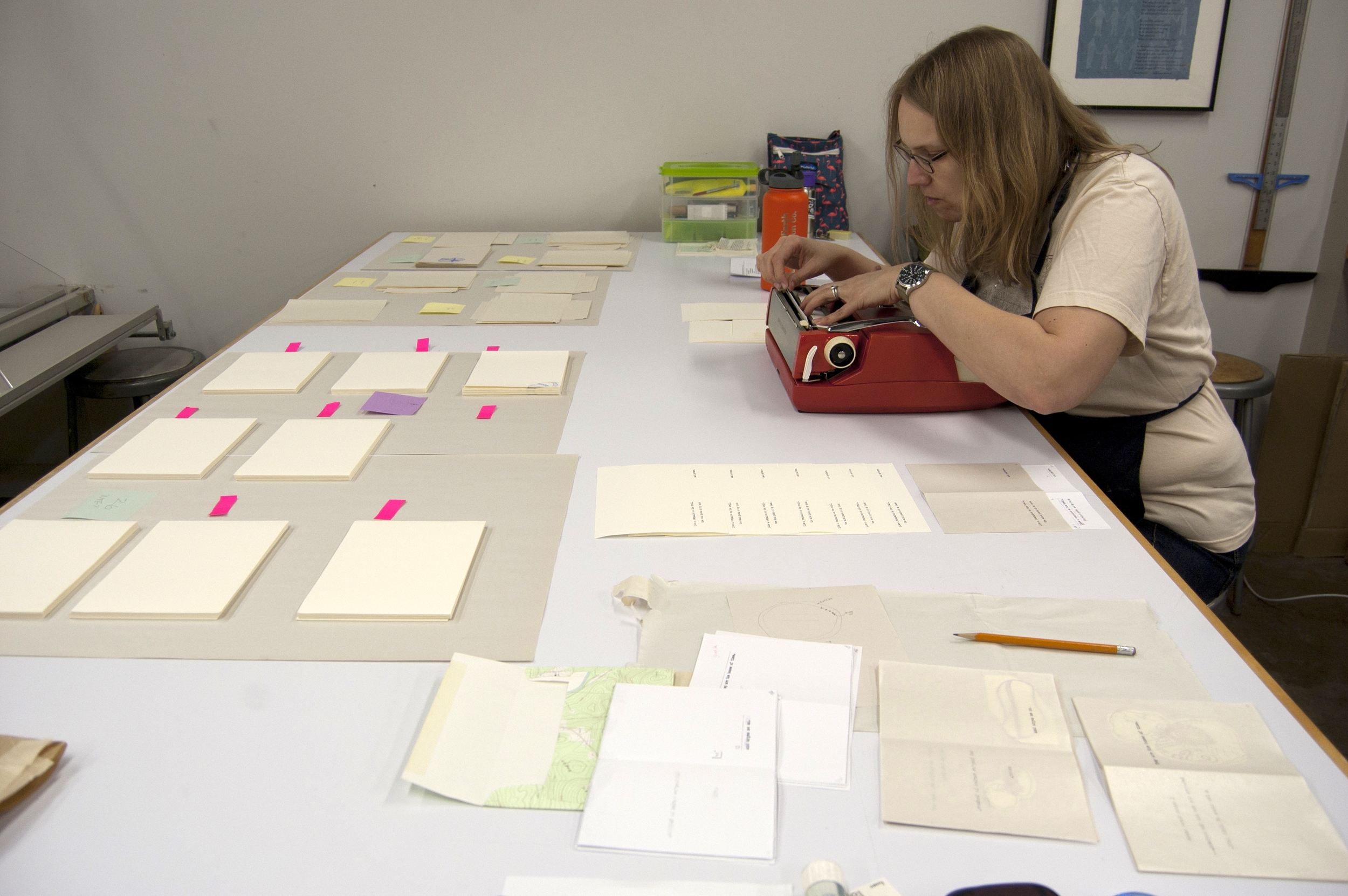 Nicole hard at work, surrounded by stacks of pages from the book.