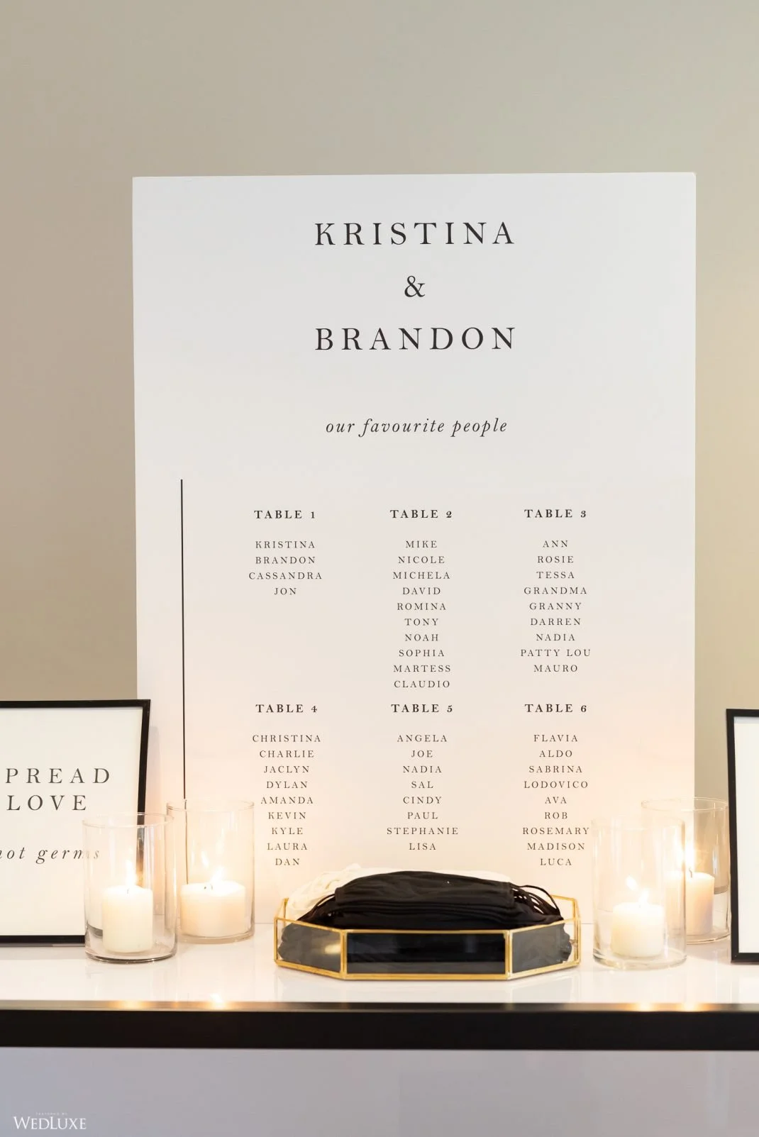 Wedding seating chart with tables and guest names, candles, and signs.