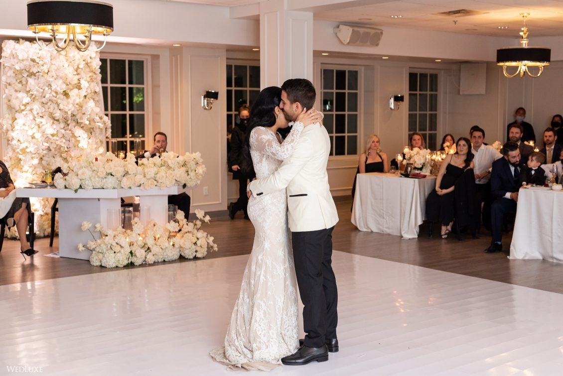 A bride and groom sharing their first dance at a wedding reception, surrounded by seated guests in a decorated venue.