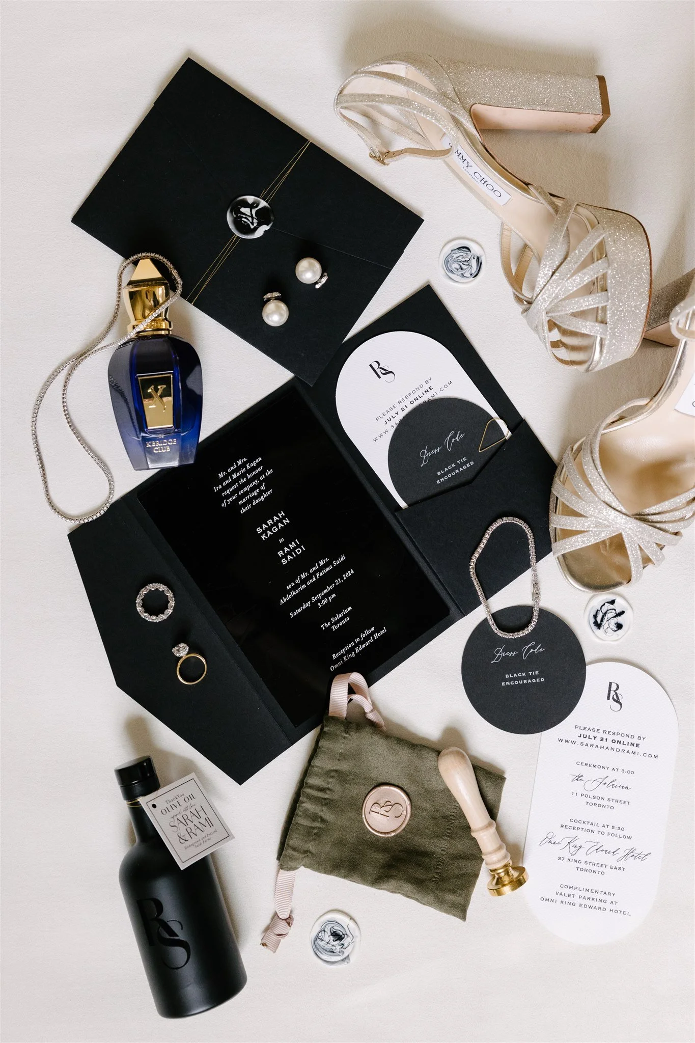 Wedding invitation, jewelry, perfume, shoes, and a wedding vow recording device arranged on a surface.