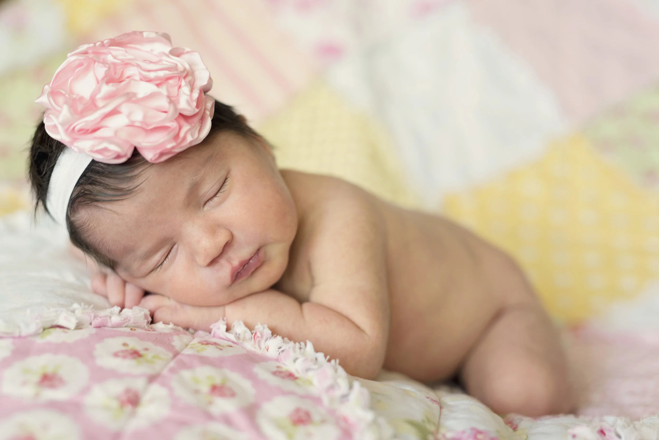 newborn girl with quilt and pink bow