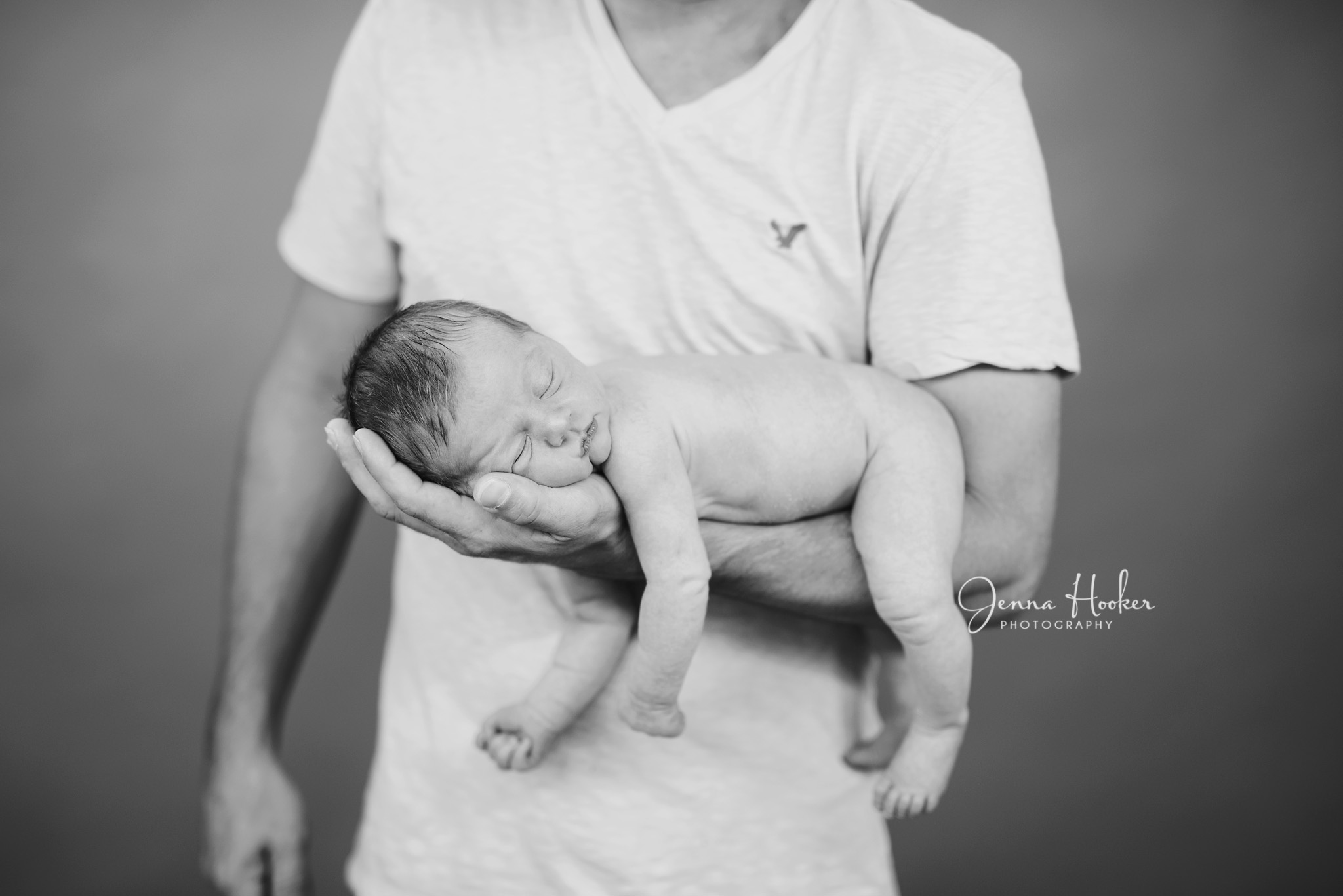 relaxed newborn in daddys arms