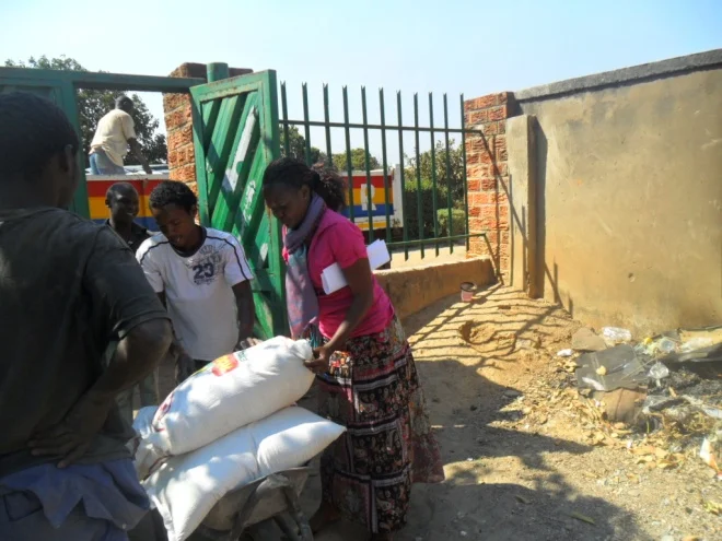 Chomba Mwiche CAM volunteer secretary (in pink) and the boys volunteering to offload the bags of mealie meal from CHAT Milling truck, the incentives we enjoy by buying from these two milling companies