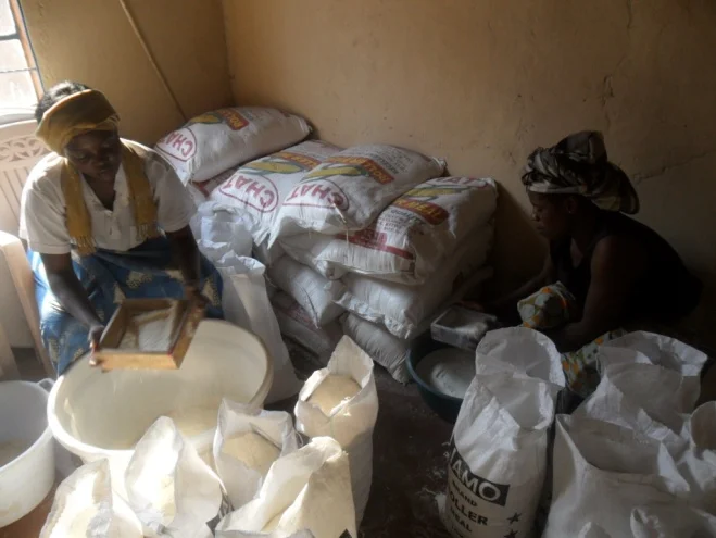 Bernadette (Stan’s wife) (r), and Mwiche Chomba (l) repacking mealie meal in the storeroom at CAM office at 3038 Kwacha East Kitwe, Zambia, in readiness for distribution to the needy chronically ill TB/HIVAIDS patients in the communities