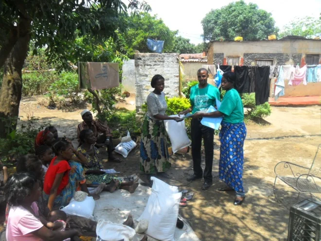 Stanley and Mwiche giving mealie meal to Mary Makungu in Buchi community