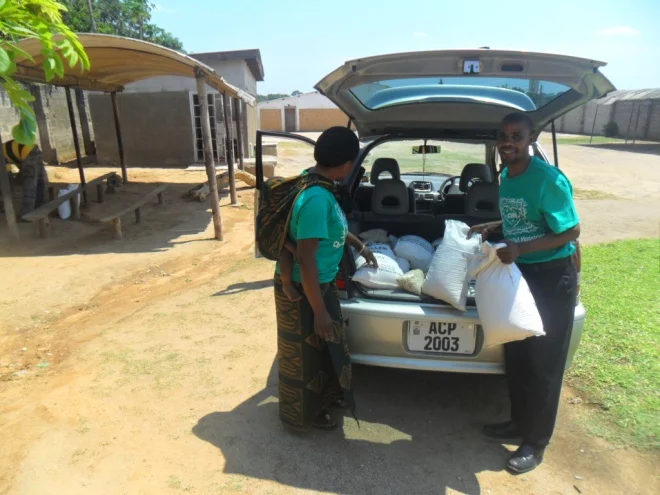 Stanley and Bernadette offloading mealie meal and beans from a hired vehicle in readiness for food distribution to TB clients in kamatipa community