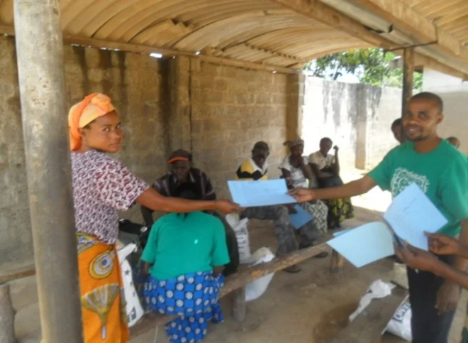 Christian Aid Ministries director Stanley Mulenga giving a Client Food Distribution Card to Mrs. Joyce Kachaka before the food distribution program started