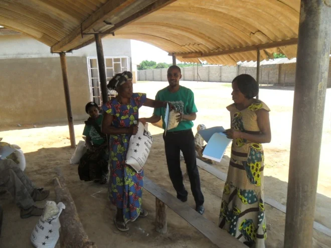 Stanley and Mary Kampyongo, kamatipa community volunteer giving melie meal and beans to Jenifer Mukwabila