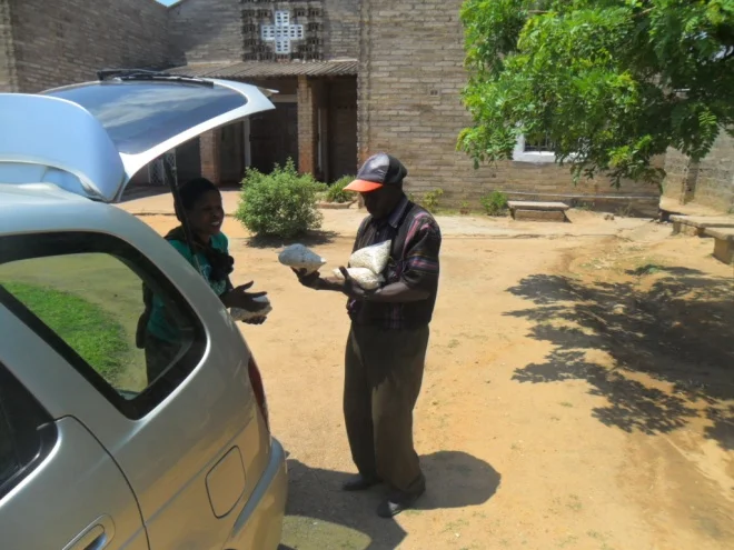 Mr. Roderick Mufwaya helping to offload food supplies from the vehicle