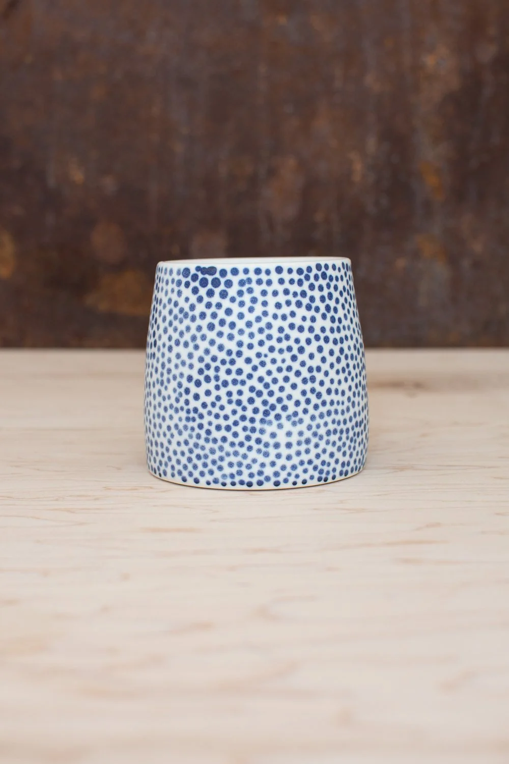 Hand-thrown porcelain mug with blue dots and a pink handle.