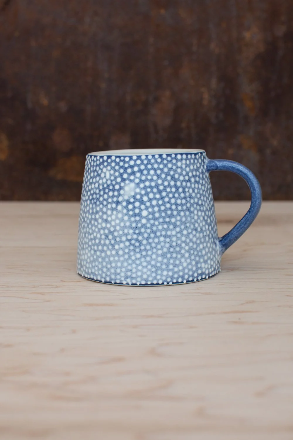 Hand-thrown porcelain mug with blue illustrations painted on the surface.