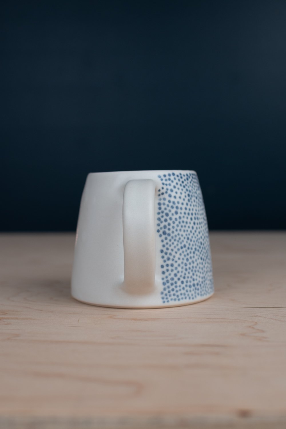 Hand-thrown porcelain mug with black illustrations painted on the surface.