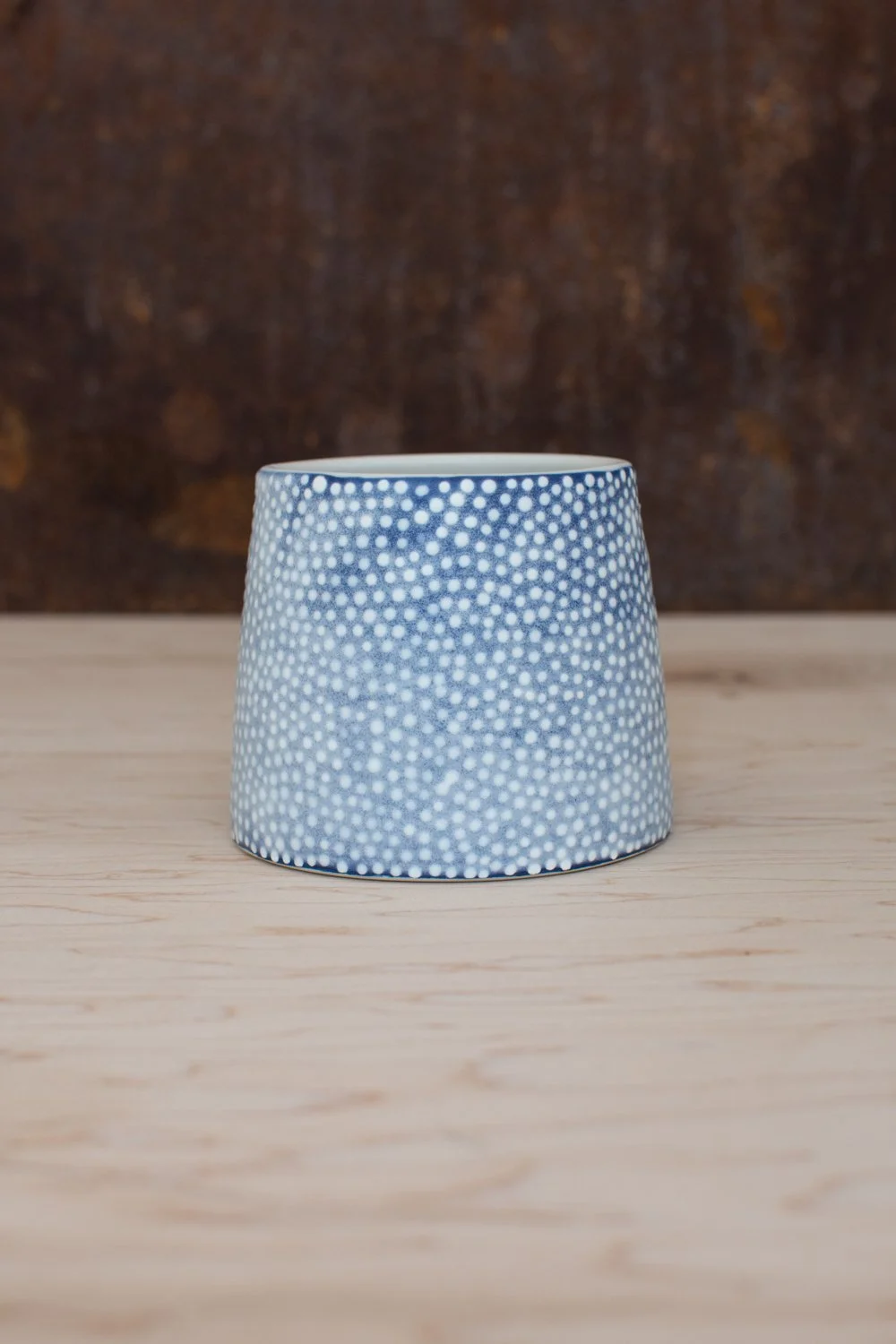 Hand-thrown porcelain mug with blue illustrations painted on the surface.