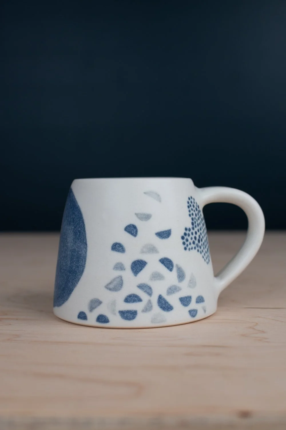 Hand-thrown porcelain mug with black illustrations painted on the surface.