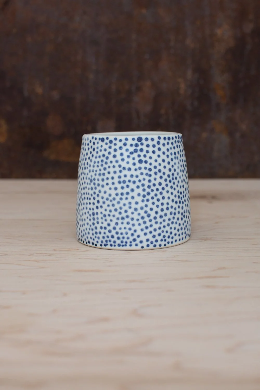 Hand-thrown porcelain mug with blue illustrations painted on the surface.