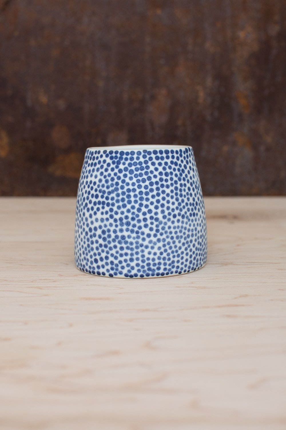 Hand-thrown porcelain mug with blue dots painted on the surface.