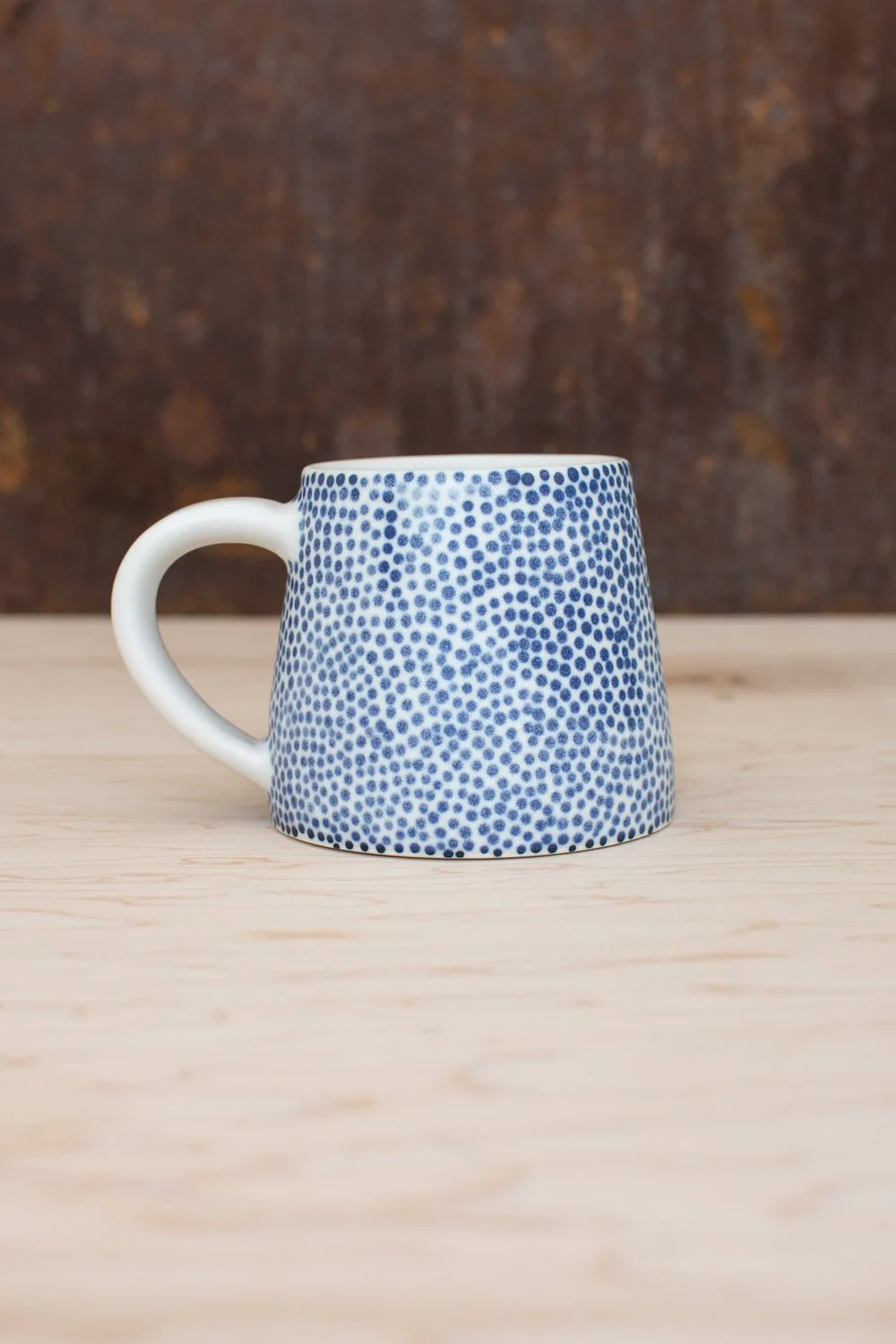 Hand-thrown porcelain mug with blue dots.