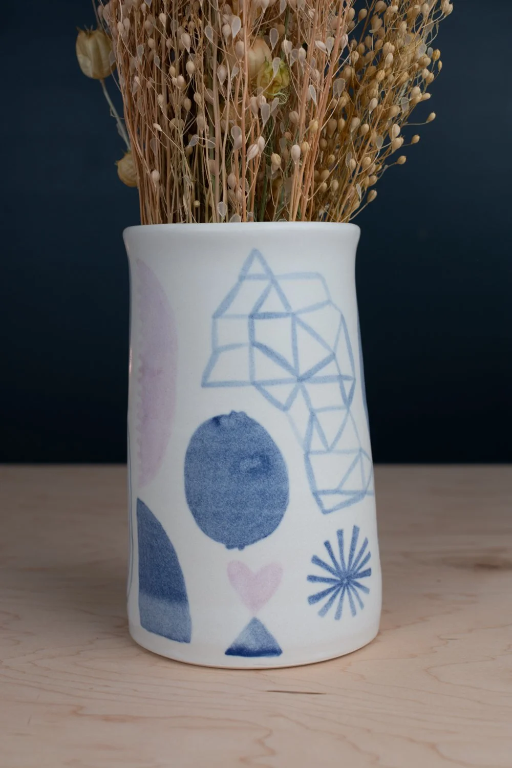 Hand-thrown porcelain vase with blue and lilac illustration.