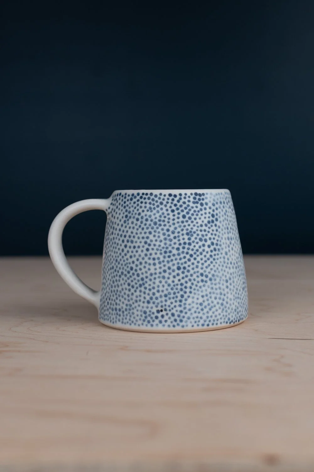 Hand-thrown porcelain mug with black illustrations painted on the surface.