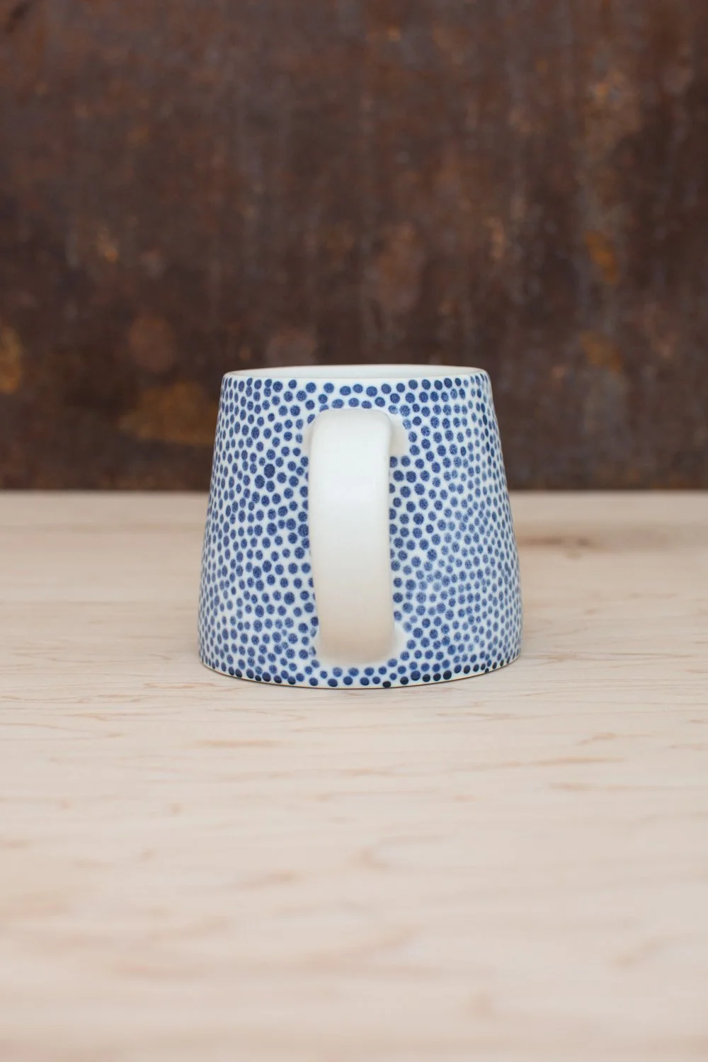 Hand-thrown porcelain mug with blue dots.