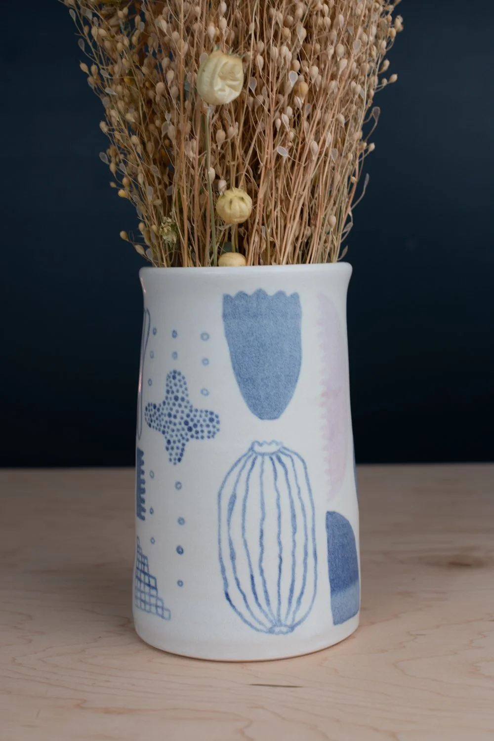Hand-thrown porcelain vase with blue and lilac illustration.