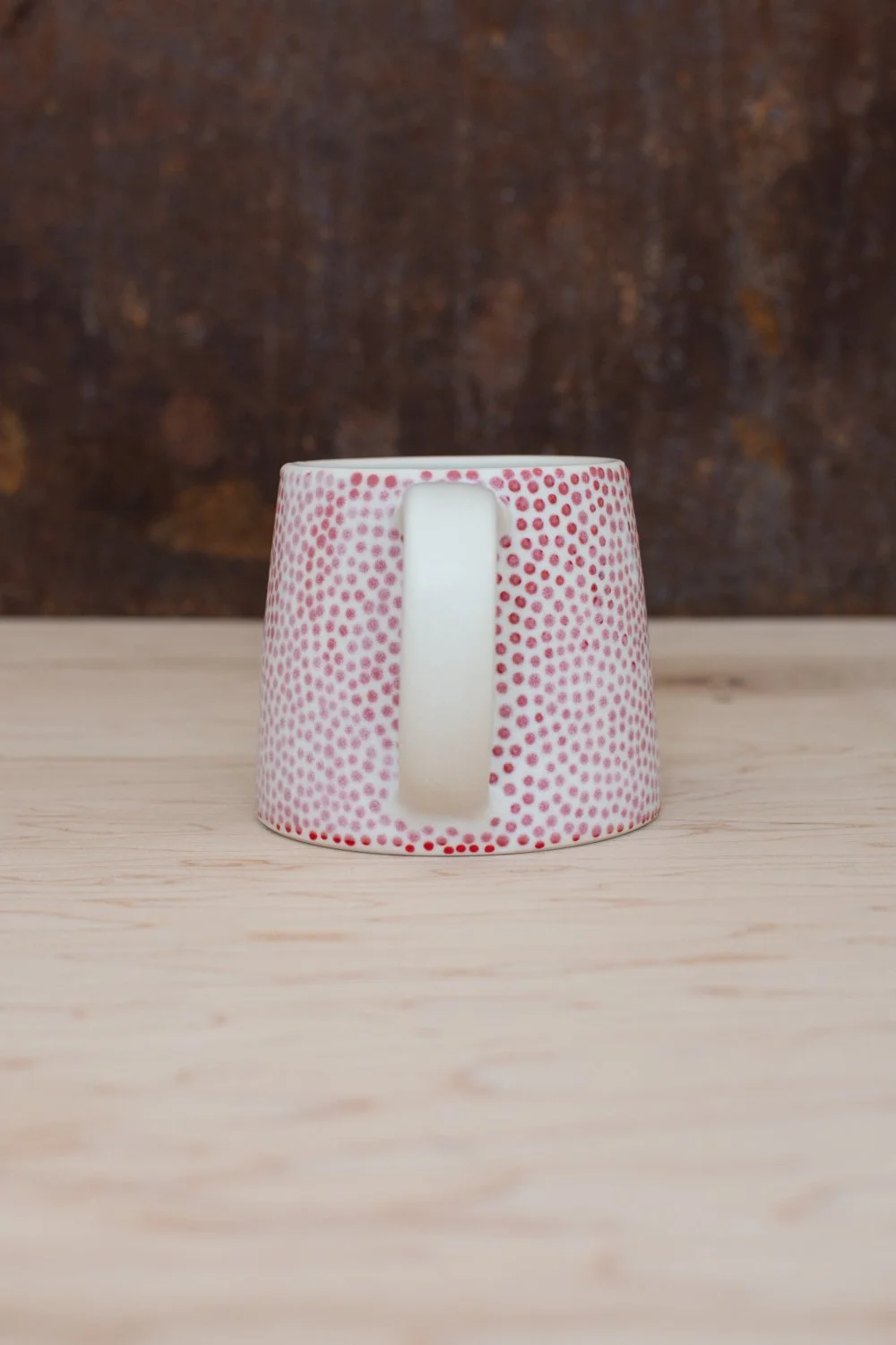 Hand-thrown porcelain mug with red dots painted on the surface.