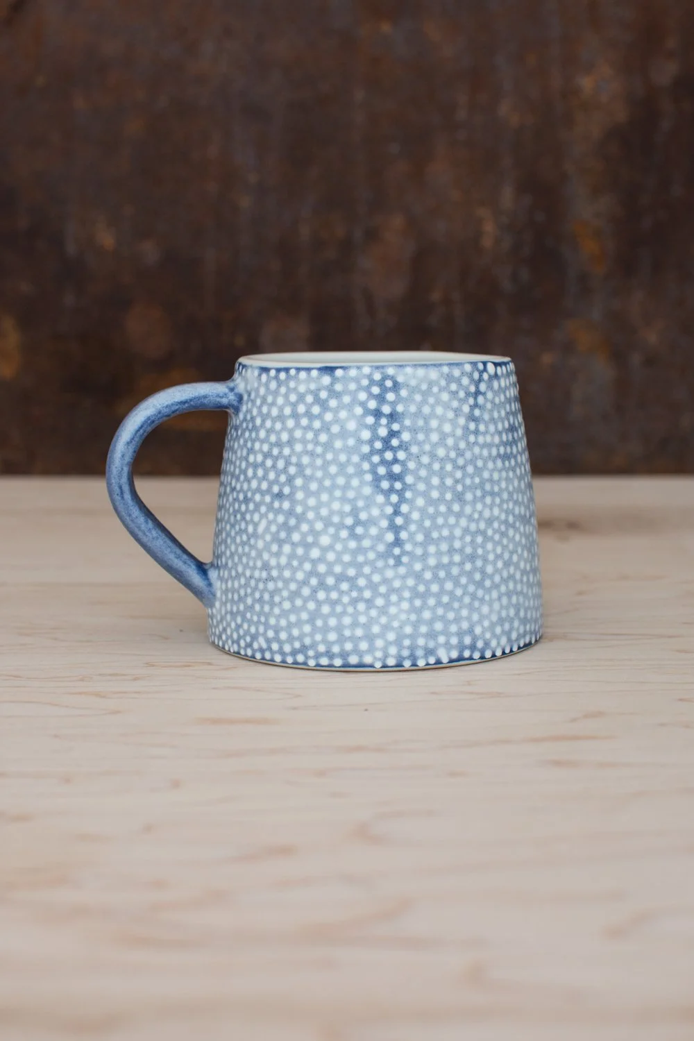 Hand-thrown porcelain mug with blue illustrations painted on the surface.
