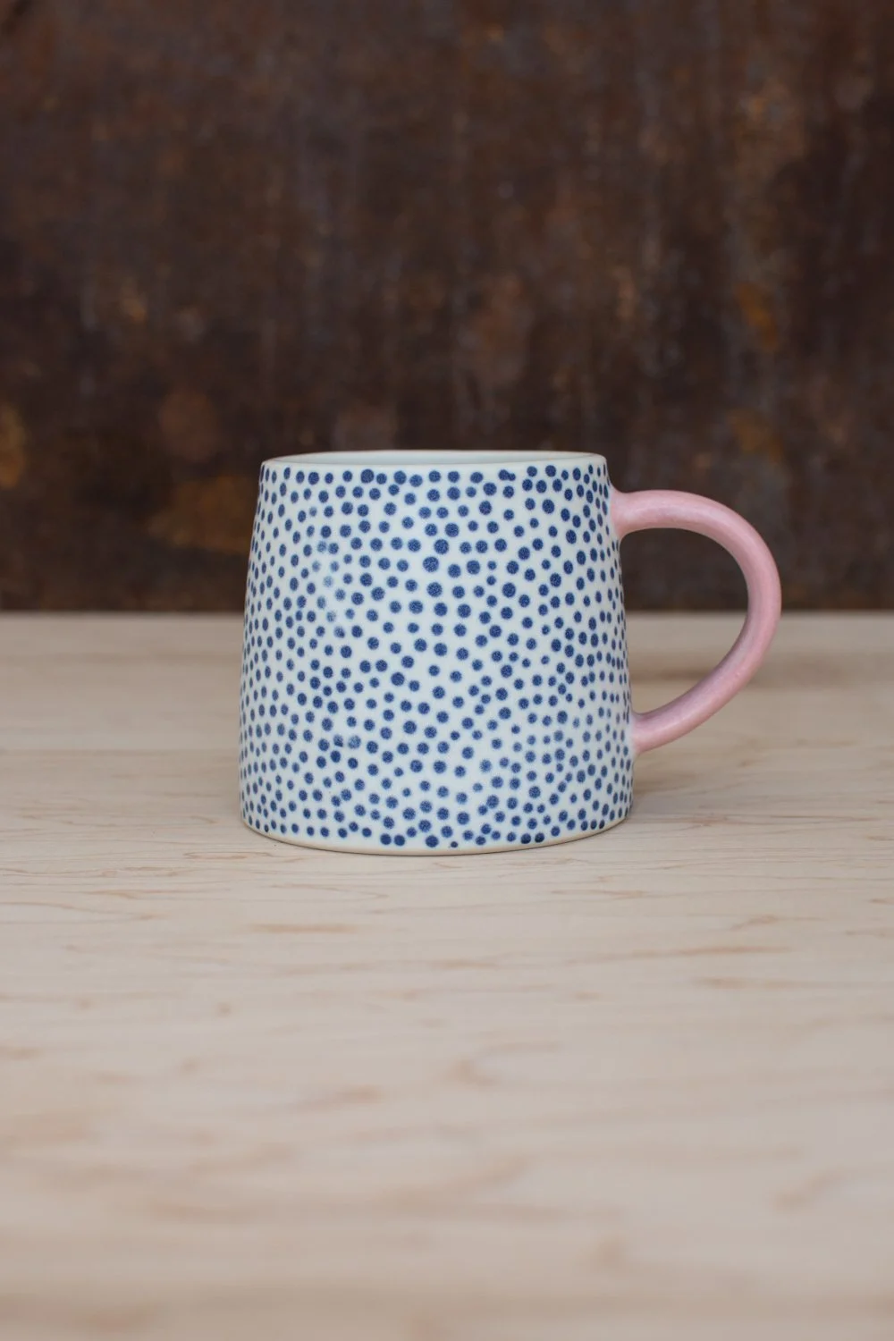 Hand-thrown porcelain mug with blue illustrations painted on the surface.