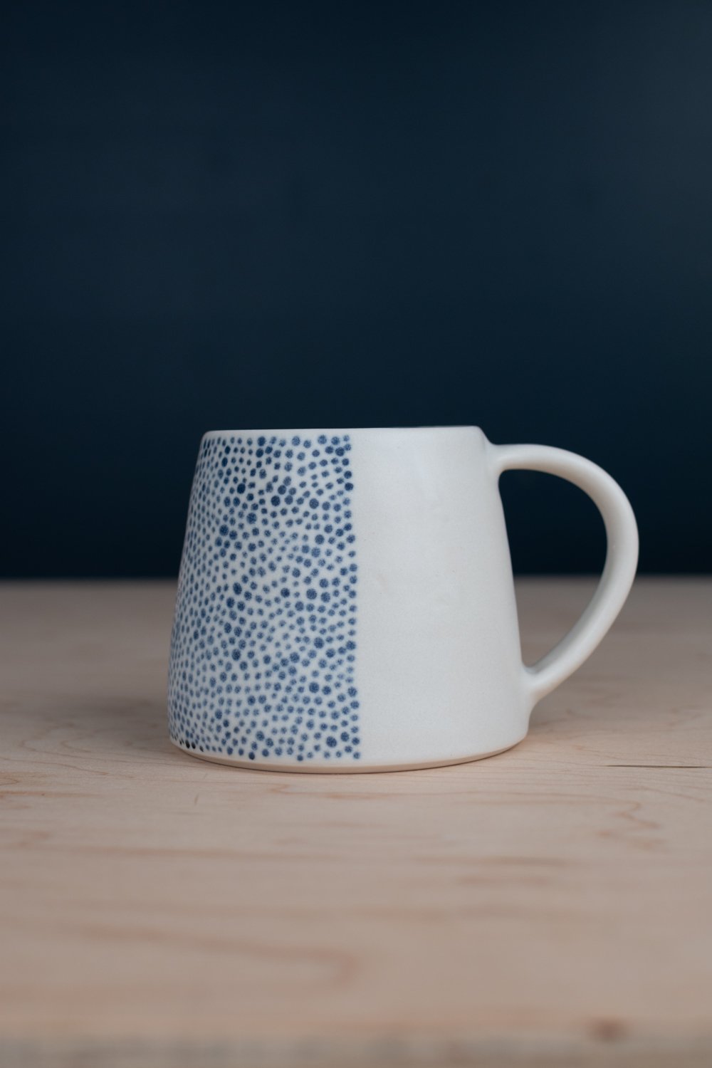 Hand-thrown porcelain mug with black illustrations painted on the surface.