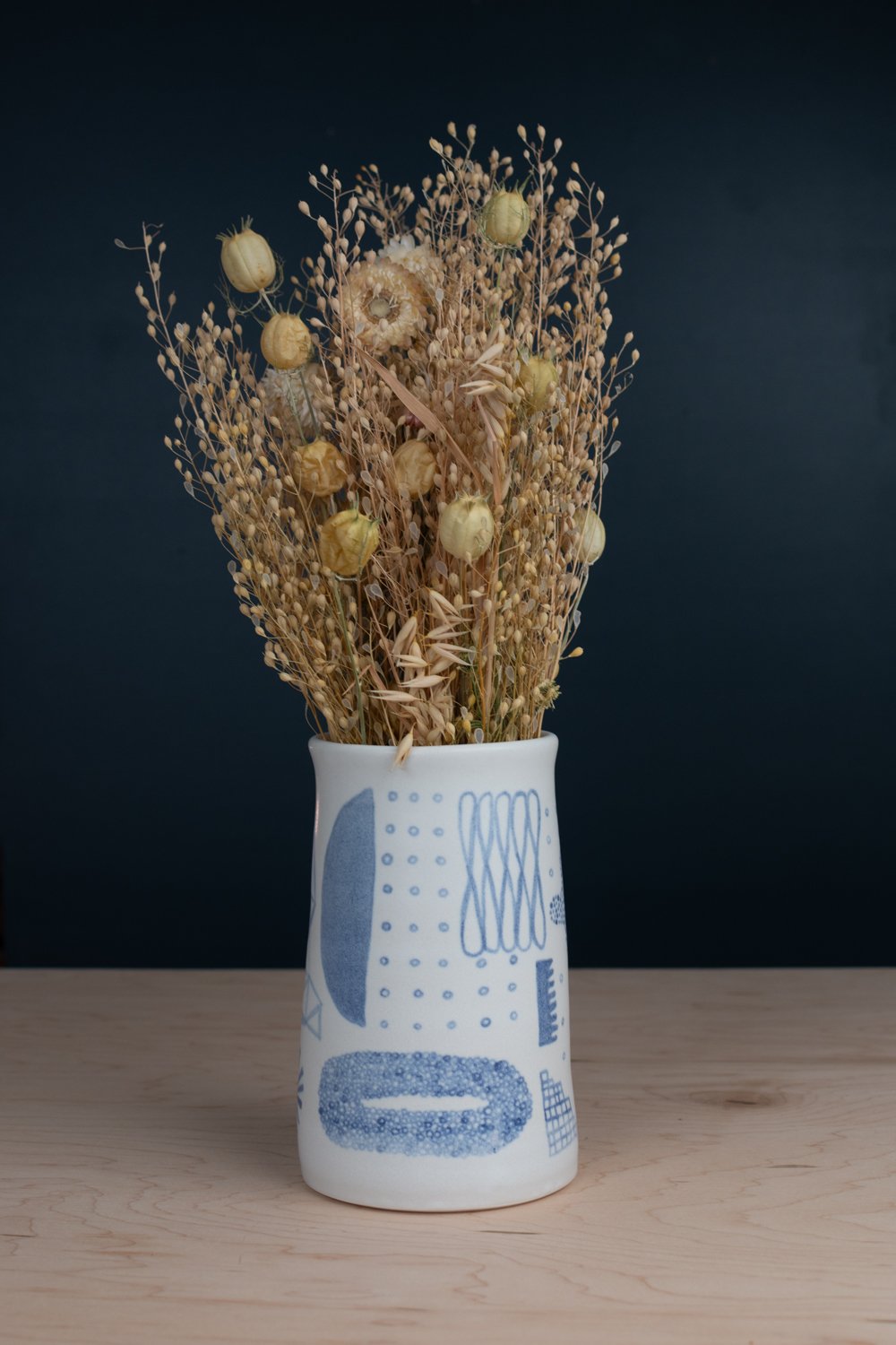 Hand-thrown porcelain vase with blue and lilac illustration.