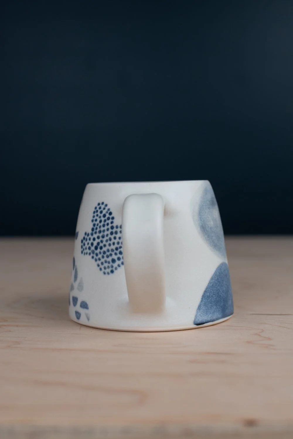 Hand-thrown porcelain mug with black illustrations painted on the surface.