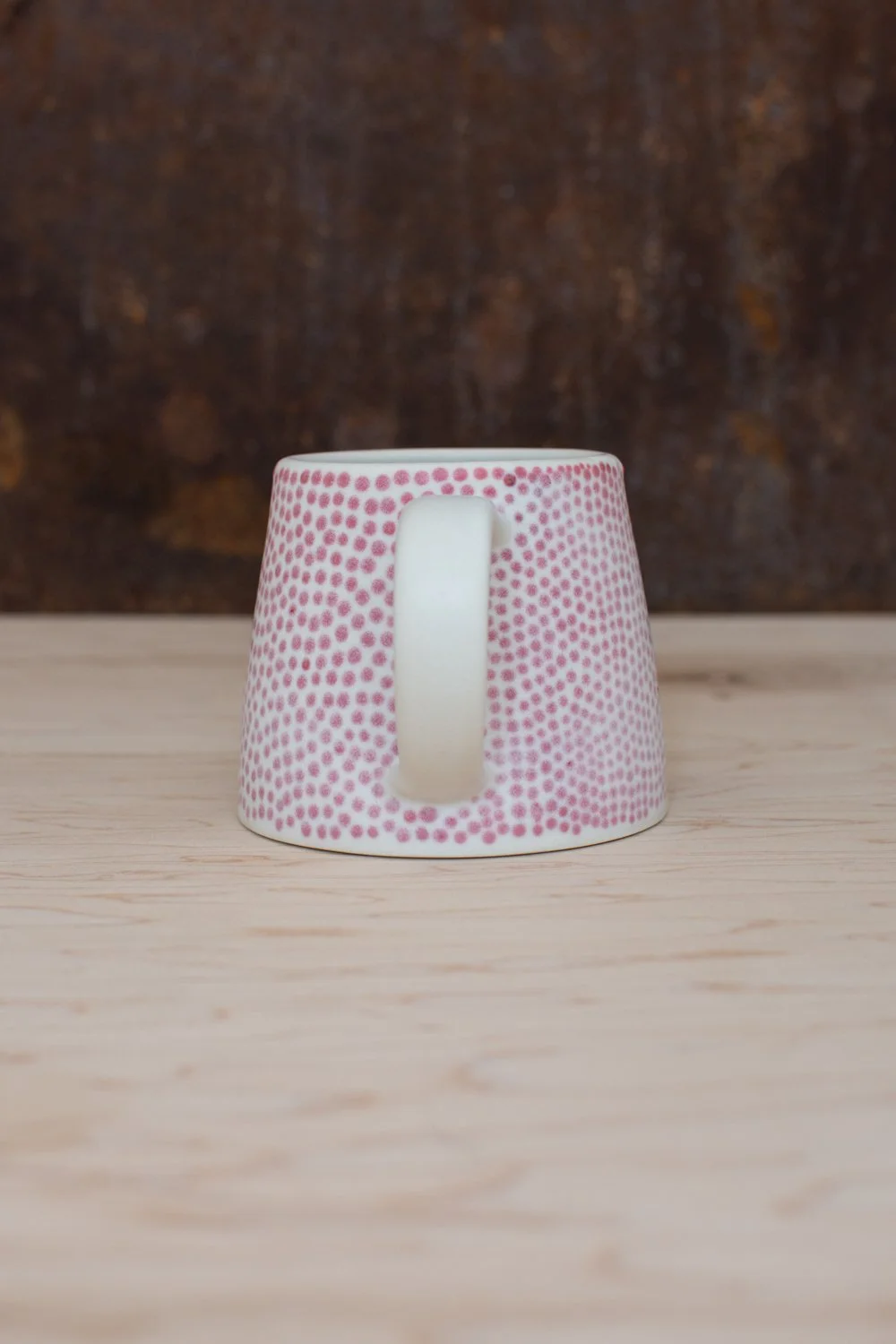 Hand-thrown porcelain mug with red dots painted on the surface.