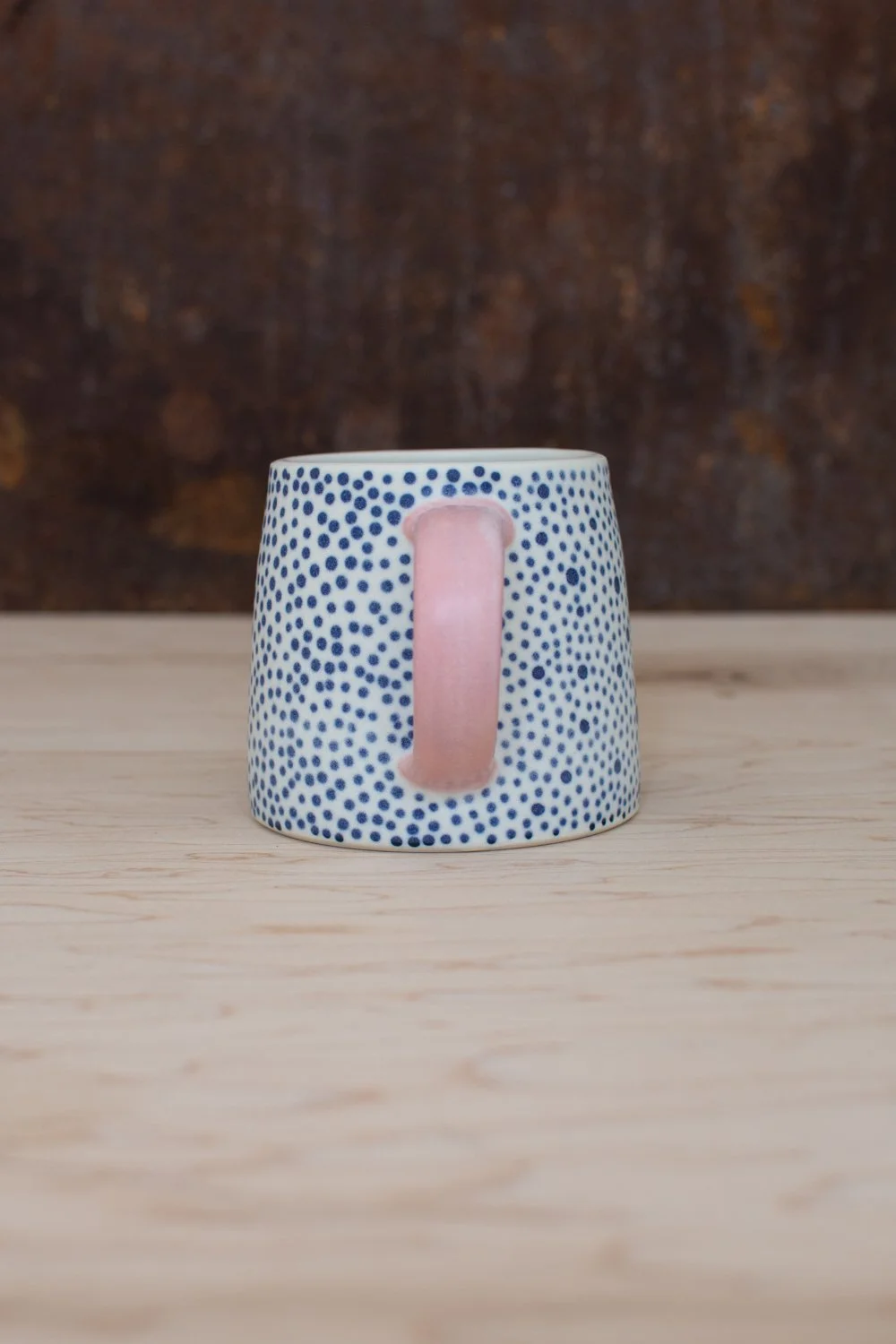 Hand-thrown porcelain mug with blue illustrations painted on the surface.