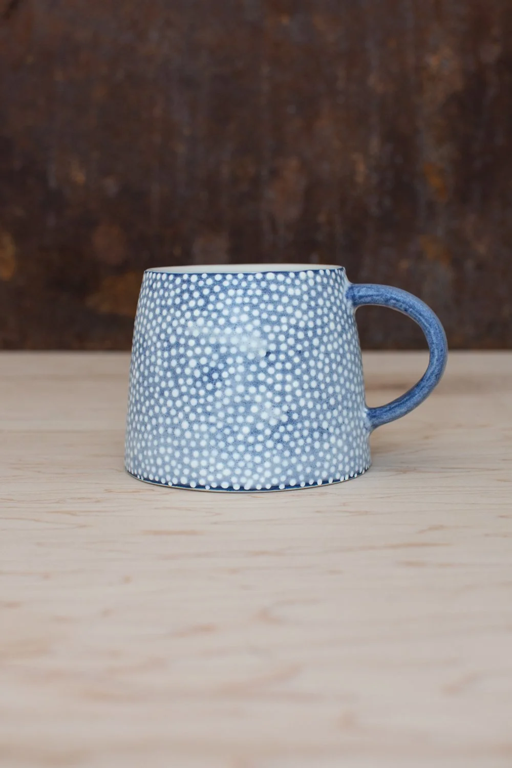 Hand-thrown porcelain mug with blue illustrations painted on the surface.