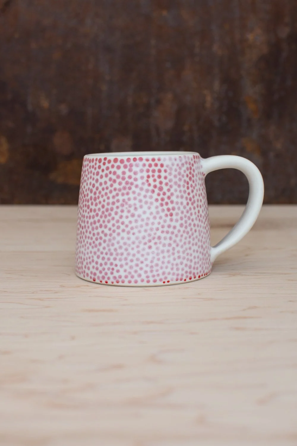 Hand-thrown porcelain mug with red dots painted on the surface.