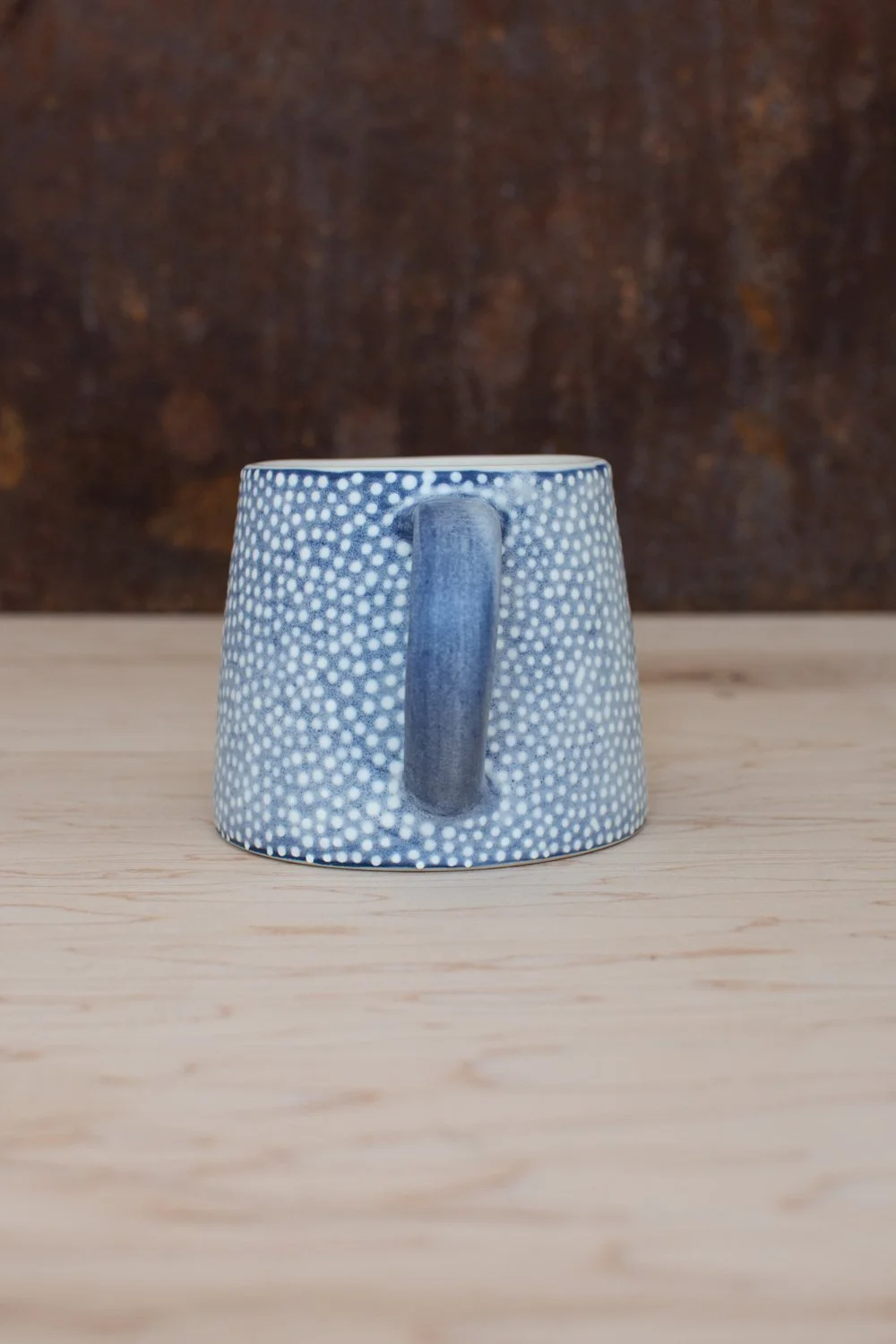Hand-thrown porcelain mug with blue illustrations painted on the surface.