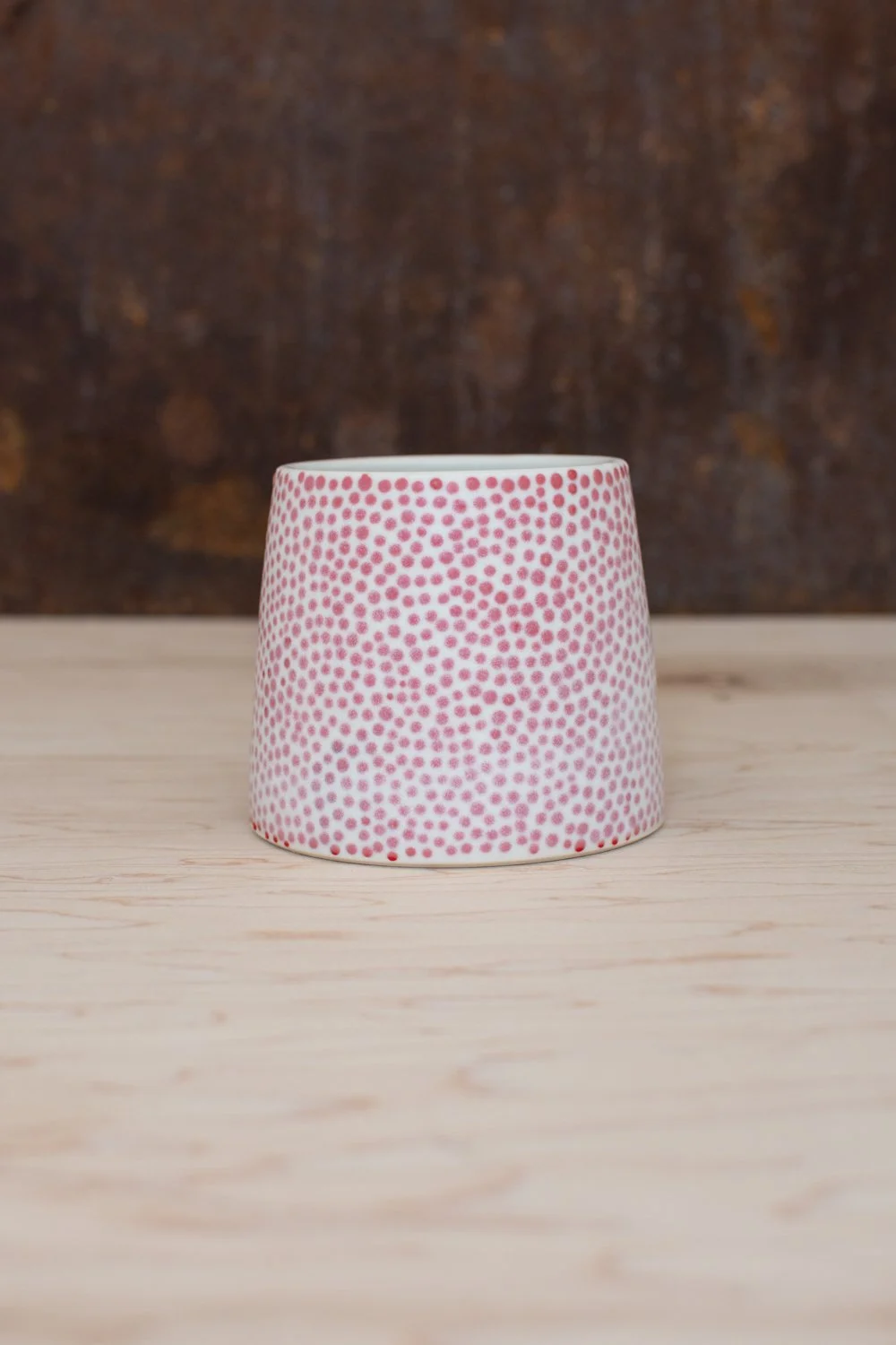 Hand-thrown porcelain mug with red dots painted on the surface.