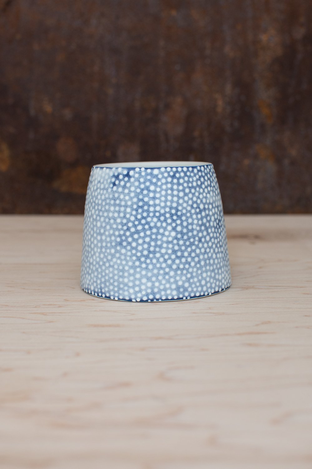 Hand-thrown porcelain mug with blue illustrations painted on the surface.