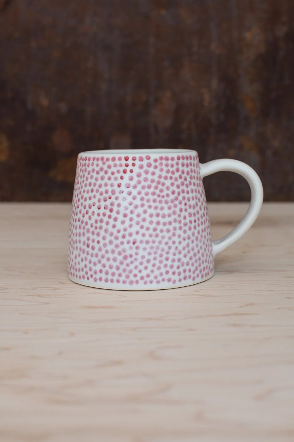 Hand-thrown porcelain mug with red dots painted on the surface.