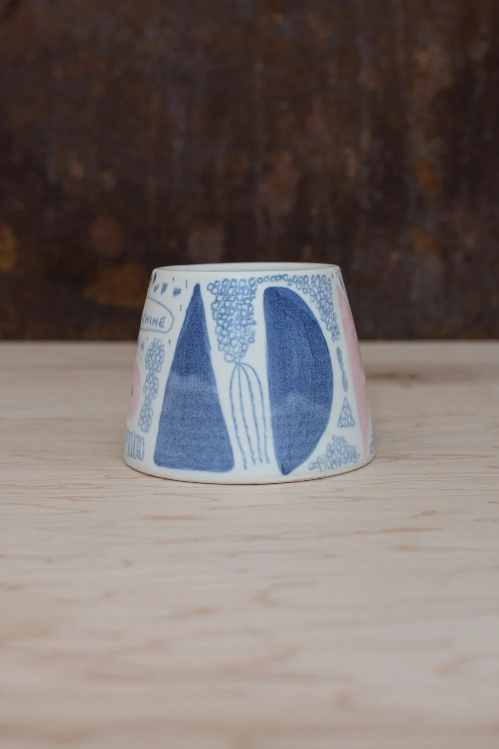 Hand-thrown porcelain mug with blue illustrations painted on the surface.