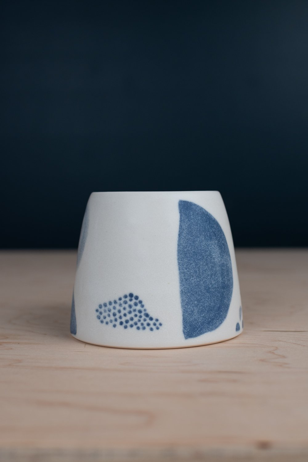 Hand-thrown porcelain mug with black illustrations painted on the surface.