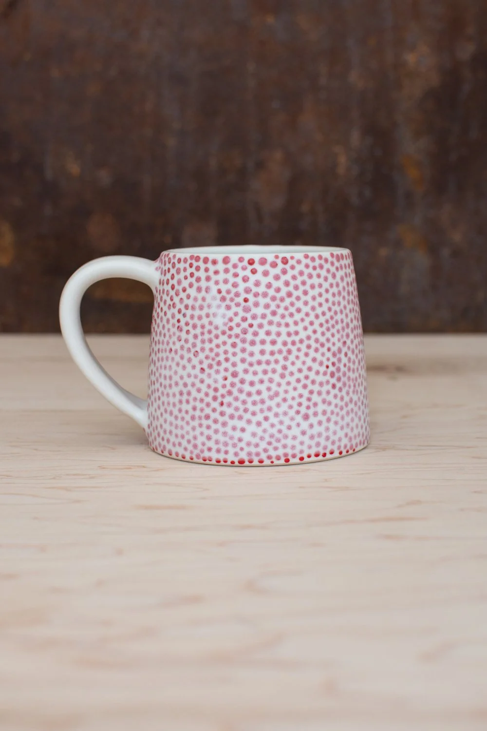 Hand-thrown porcelain mug with red dots painted on the surface.