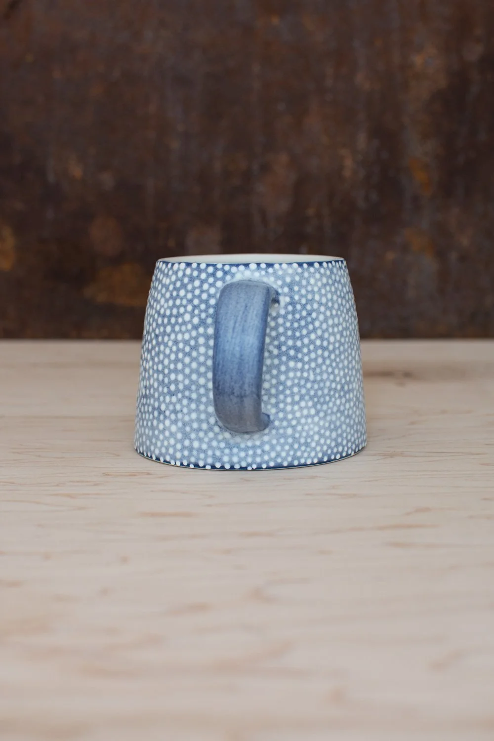 Hand-thrown porcelain mug with blue illustrations painted on the surface.