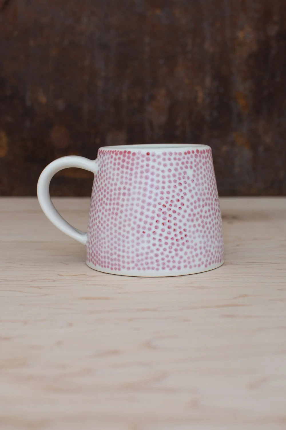 Hand-thrown porcelain mug with red dots painted on the surface.