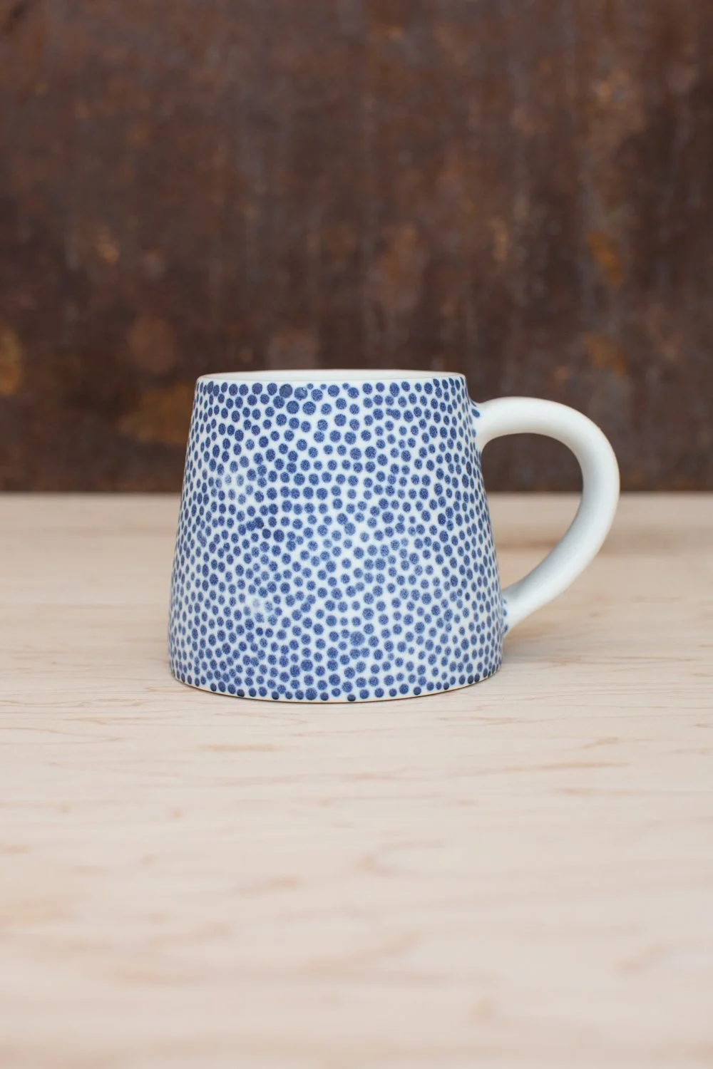 Hand-thrown porcelain mug with blue dots.