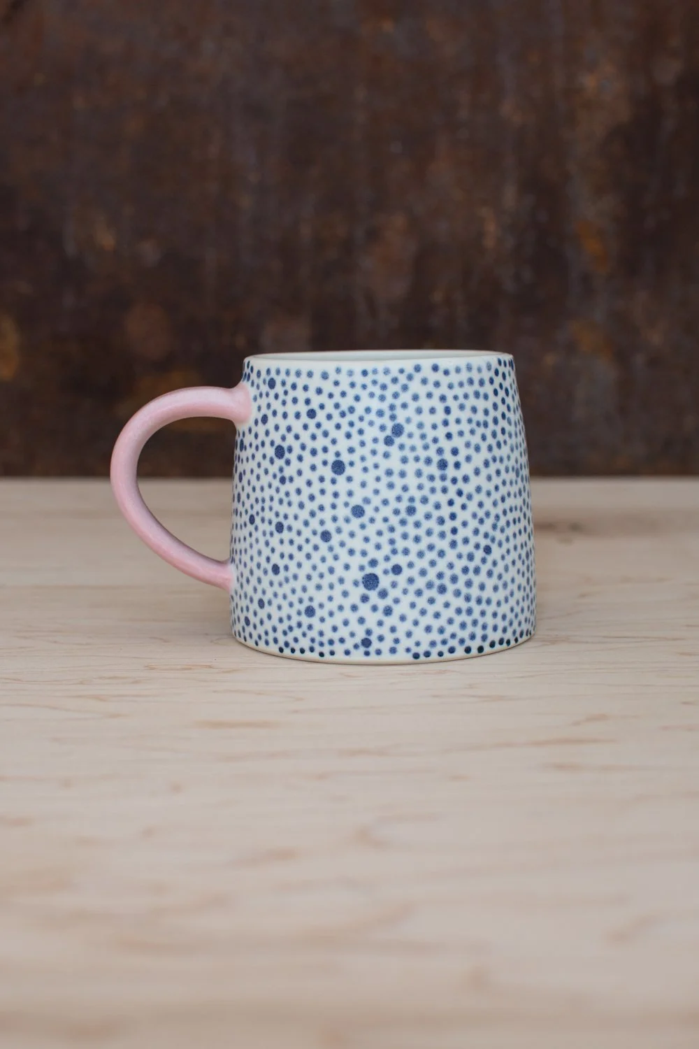 Hand-thrown porcelain mug with blue illustrations painted on the surface.